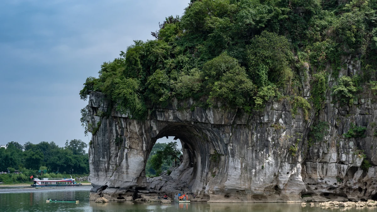 Elephant Trunk Hill Water Moon Cave circular arch reflection in the Li River with traditional bamboo raft and willow trees